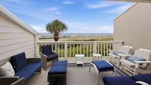 Ein Balkon mit Sitzmöbeln, Blick auf den Strand und eine Palme.