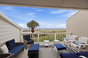 A balcony with outdoor furniture, a view of the beach, and a palm tree. - Modern Oceanfront Beach Club Villa *Unit 4* in Wild Dunes w/Community Pool! Screen Porch!! (Isle Of Palms)