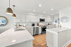 A modern kitchen with white cabinetry, a central island, stainless steel appliances, and a hanging pendant light. - Modern Oceanfront Beach Club Villa *Unit 4* in Wild Dunes w/Community Pool! Screen Porch!! (Isle Of Palms)