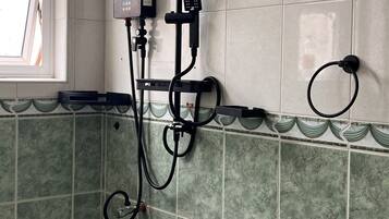 Une salle de bain équipée d’une douche, de toilettes et d’une fenêtre.