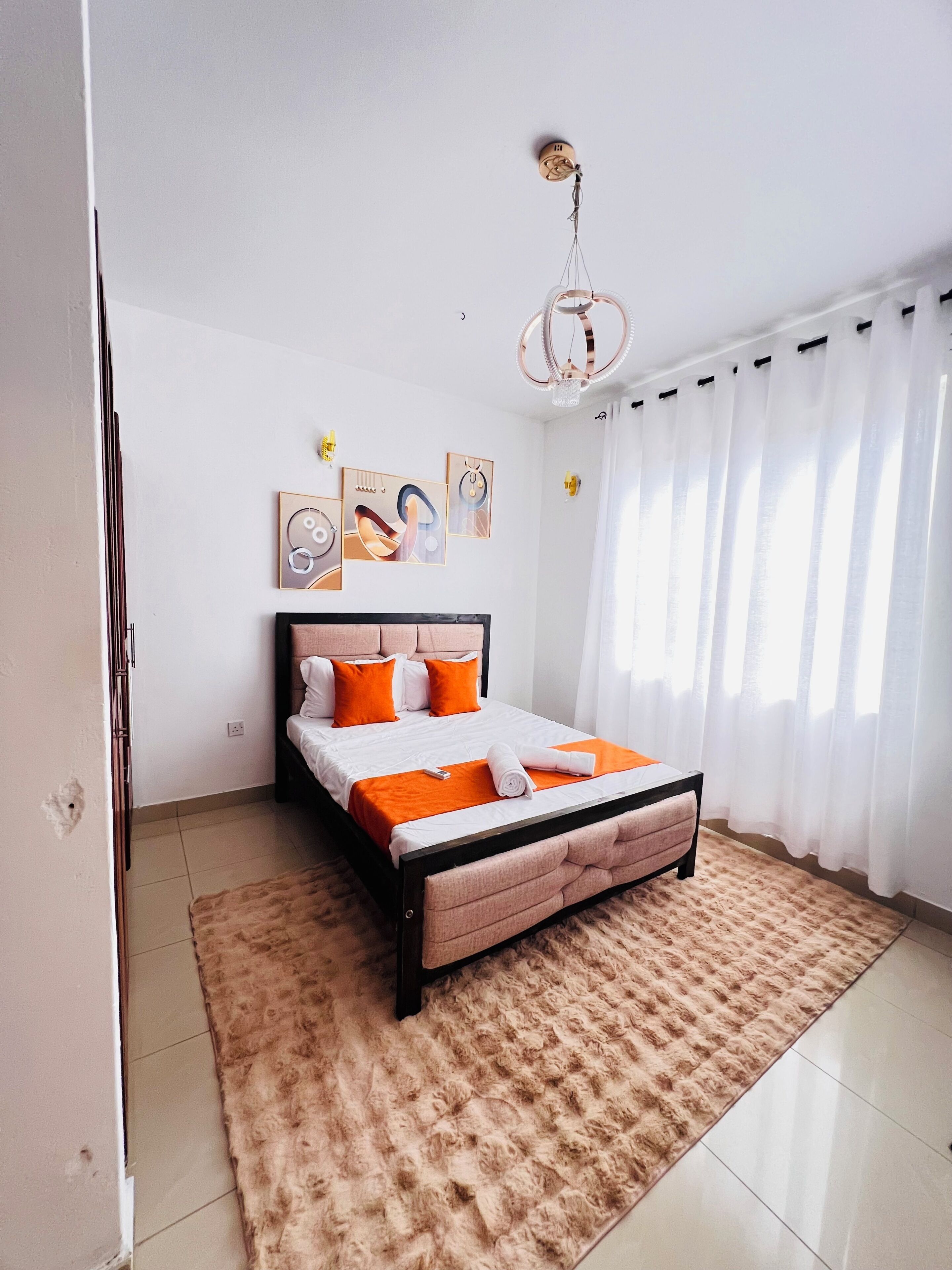 Ein Schlafzimmer mit Bett, Teppich, Vorhängen und Wandbildern.