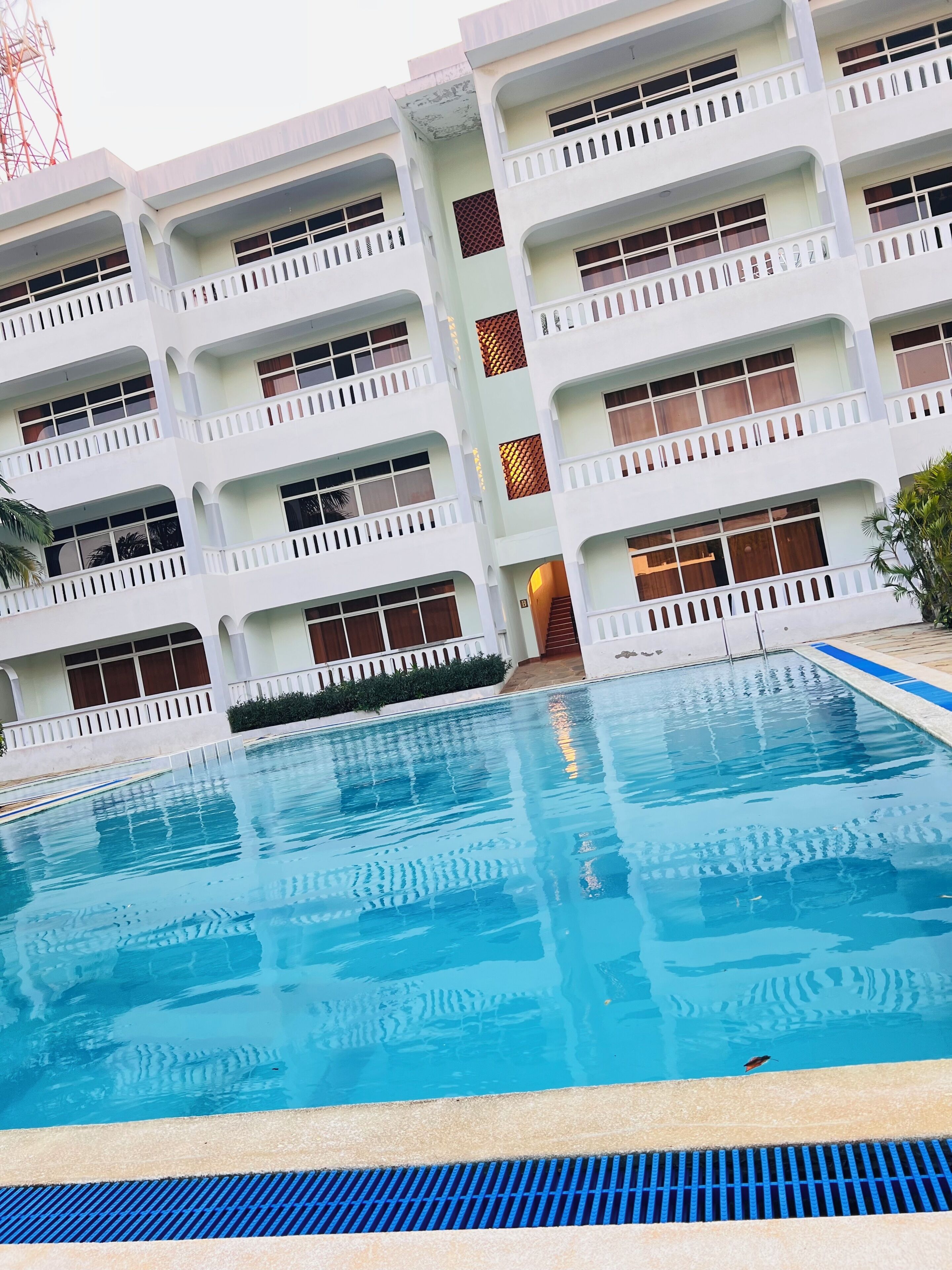 Ein mehrstöckiges Hotel mit einem Schwimmbecken im Vordergrund.