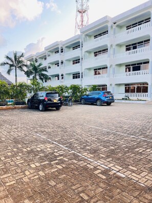 Un edificio de varios pisos con un área de estacionamiento al frente.
