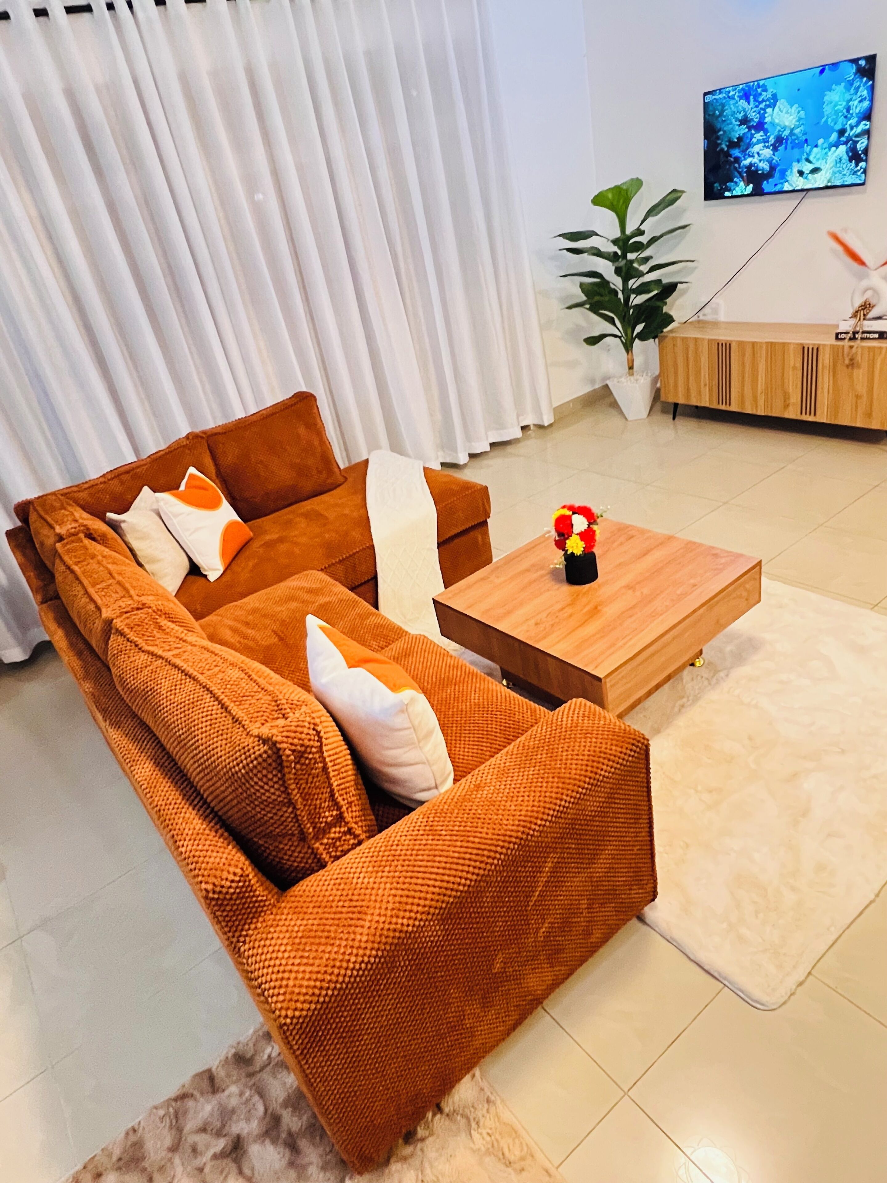 Ein modernes Wohnzimmer mit einem braunen Sofagarnitur, einem Holztisch und einem flachbildfernseher an der Wand.