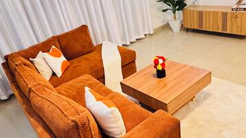 Ein modernes Wohnzimmer mit einem braunen Sofagarnitur, einem Holztisch und einem flachbildfernseher an der Wand.