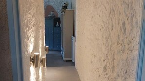 A hallway with a textured wall, a cabinet with drawers, and a door with a plant on top. - Unique troglodyte cave - 4 guests (Nazelles-Négron)