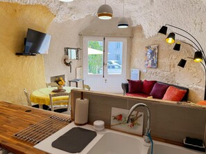 Une cuisine compacte dotée d’un plan de travail en bois, d’un évier et d’un coin repas avec une nappe jaune.