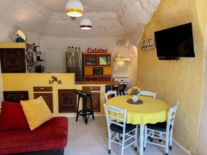 Eine kleine Küche mit Essbereich, einem roten Sofa und einem an der Wand befestigten Fernseher.