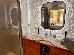 Une salle de bain avec un meuble-lavabo en marbre, un grand miroir et un espace douche.