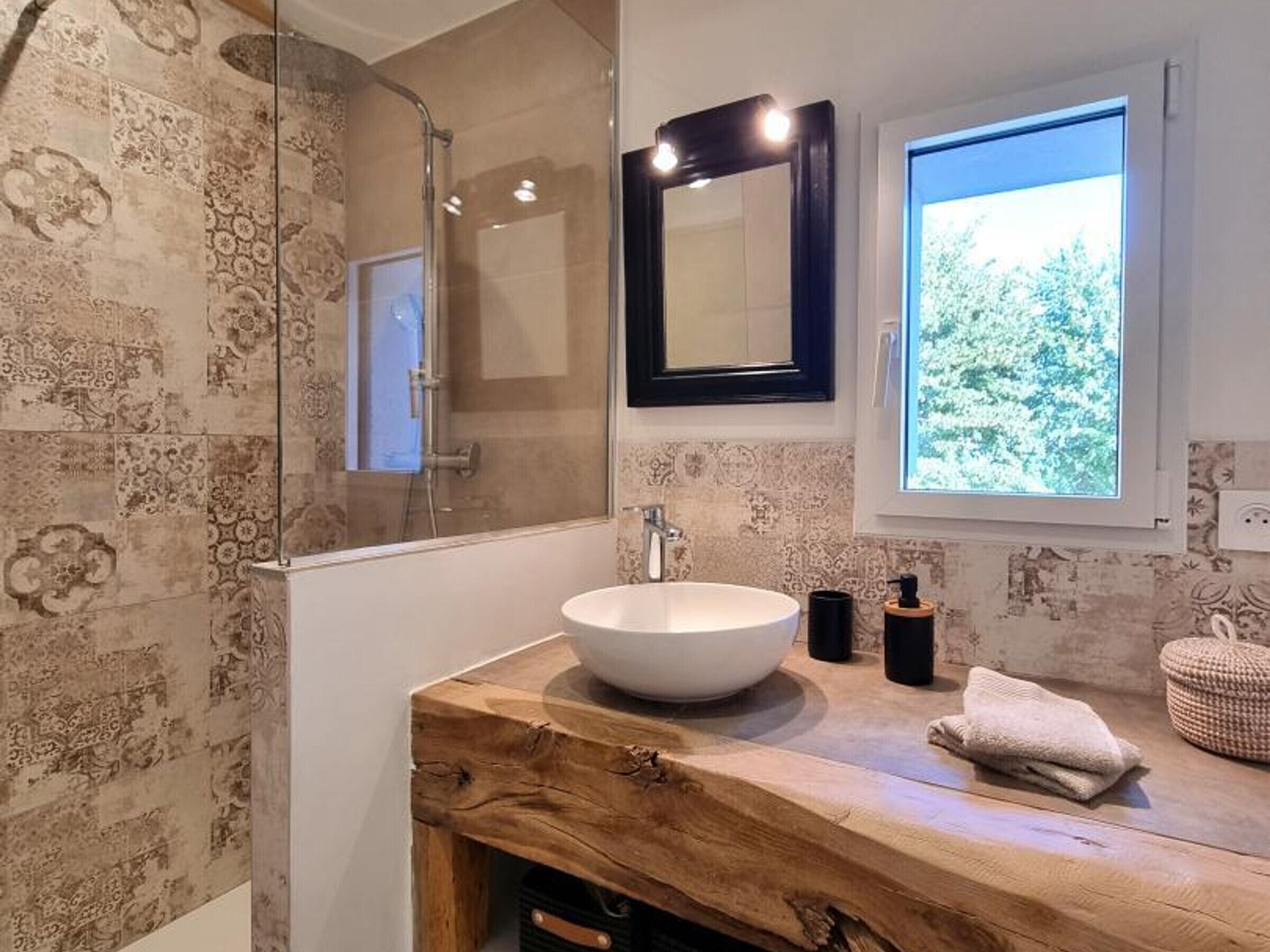 A bathroom with a large mirror, a sink, and a shower.