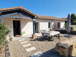 Ein Haus mit einer Terrasse, einem Tisch mit Stühlen und einer Steinmauer.