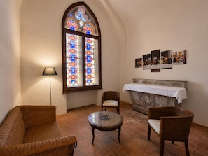 Ein Zimmer mit einem großen Buntglasfenster, einem Kamin und einem Tisch mit Stühlen.