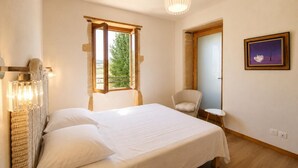 A bedroom with a bed, a chair, a small table, a window, and a painting on the wall. - House with pool and AC - 12 guests (CHANDON)