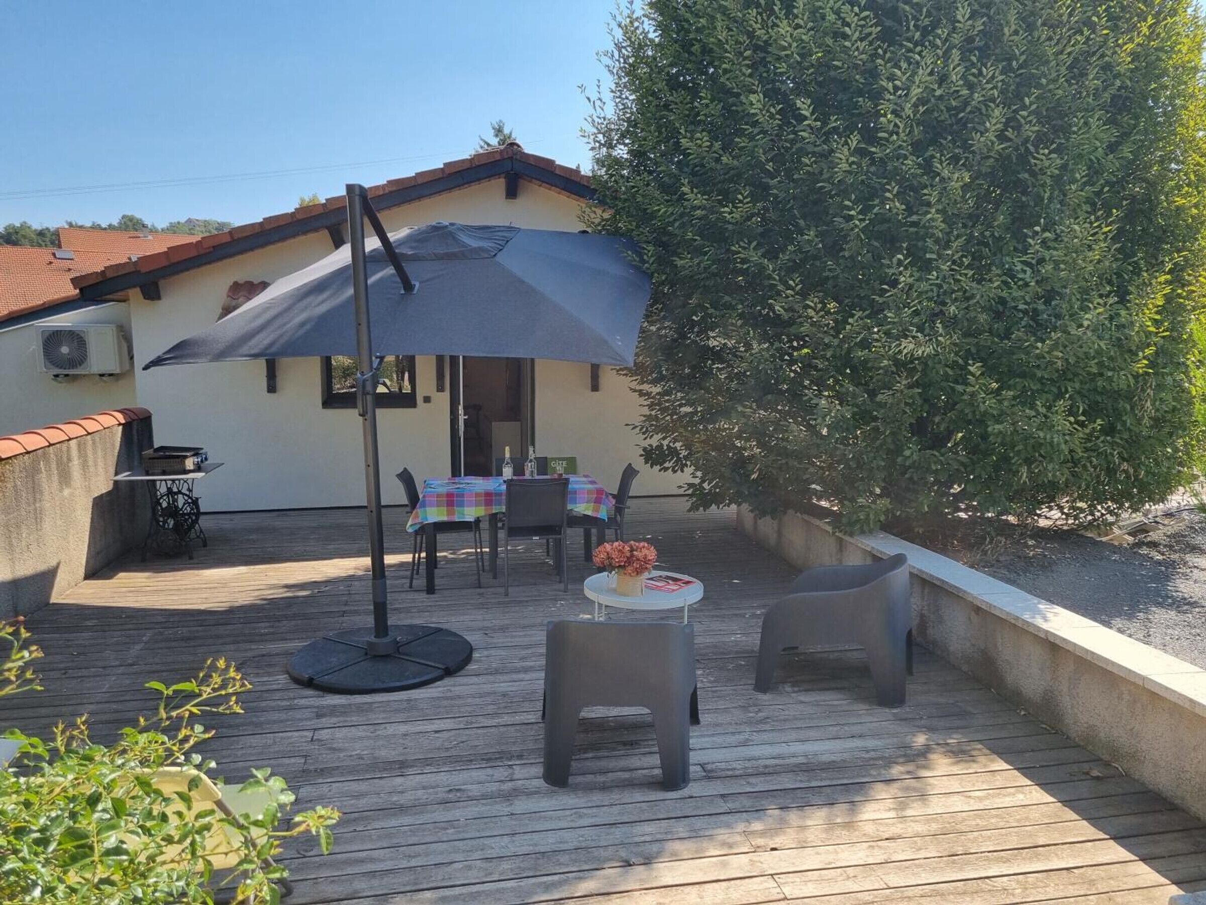 An outdoor patio with a table and chairs, a covered area, and a building in the background.