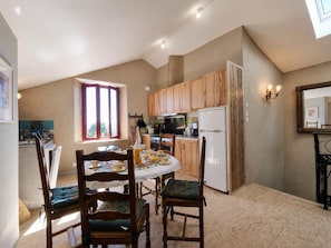 A compact kitchen with wooden cabinets, a white refrigerator, and a dining table set for four. - Authentic house in the village center - 6 guests (ROZIER COTES D'AUREC)