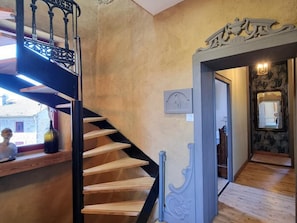 A staircase with a black railing leading to a landing, a wall with a decorative molding, and a door with a mirror and wall-mounted lights. - Authentic house in the village center - 6 guests (ROZIER COTES D'AUREC)