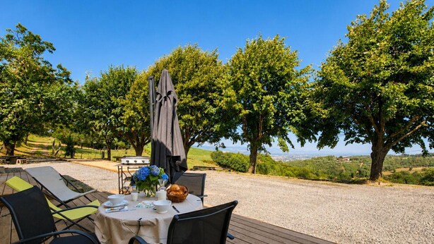 An outdoor dining area with a table set for two, surrounded by chairs, a grill, and a view of the landscape. - Cottage with countryside view - 2 guests (Saint-Just-Saint-Rambert)