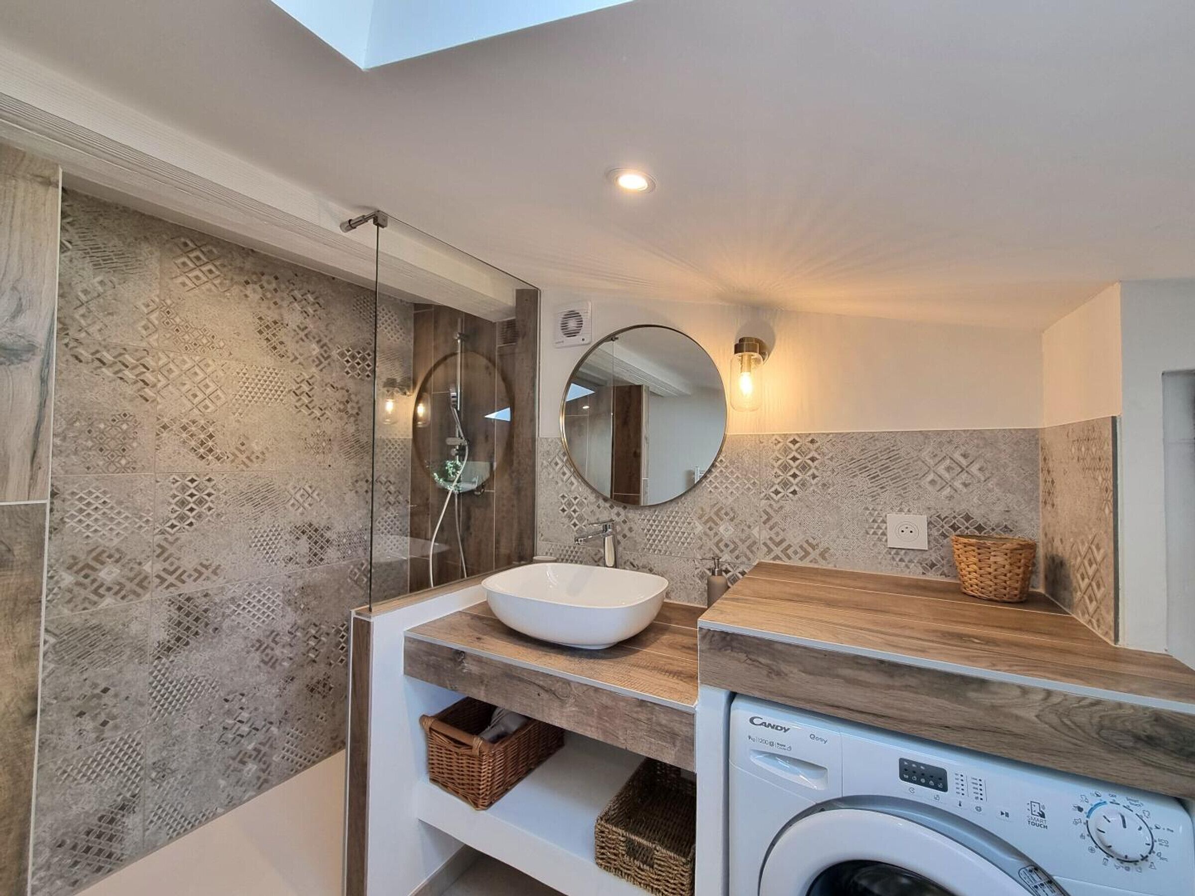 A modern bathroom with a large mirror, a sink, and a washing machine.