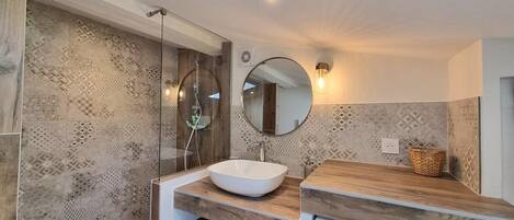 A modern bathroom with a large mirror, a sink, and a washing machine.