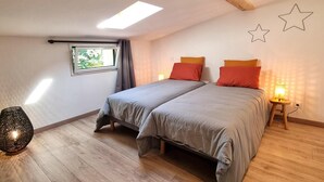 Un dormitorio con dos camas, un tragaluz, una ventana y una decoración de pared con estrellas.