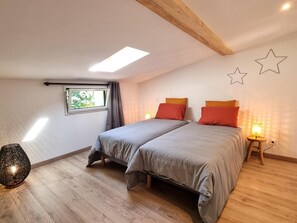 A bedroom with two beds, a skylight, a window, and a star wall decoration. - Peaceful air-conditioned lodge - 3 guests (Saint-Just-Saint-Rambert)