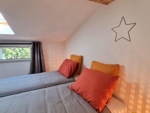 A bedroom with two beds, each with a pillow, a star decoration on the wall, and a window with curtains. - Peaceful air-conditioned lodge - 3 guests (Saint-Just-Saint-Rambert)