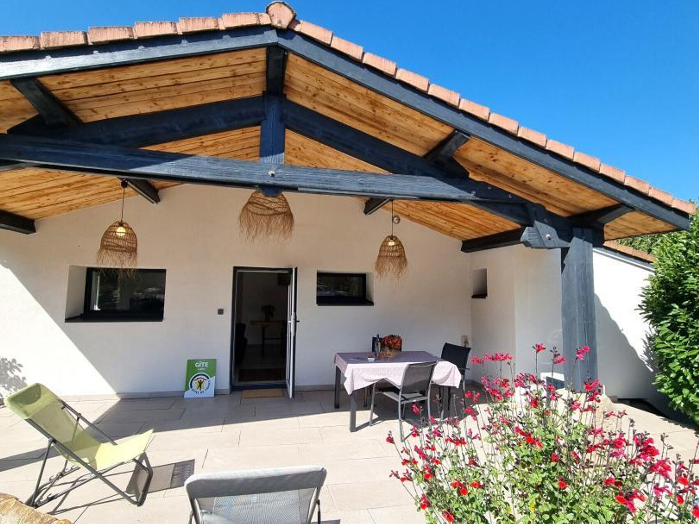 A covered outdoor seating area with a table and chairs, a door, and a sign on the wall.