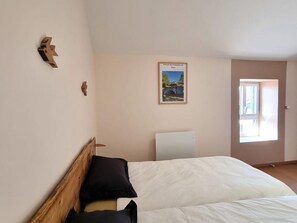 A bedroom with a bed, a wooden headboard, a poster on the wall, and a door leading to another room. - Cottage with WiFi and garden - 11 guests (SAINTE AGATHE LA BOUTERESSE)