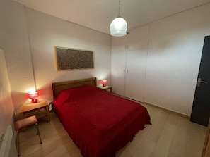 A bedroom with a single bed, two bedside tables with lamps, a wardrobe, and a hanging light fixture. - Apartment, pets welcome, sea view - 4 guests (Saint-Cyprien)