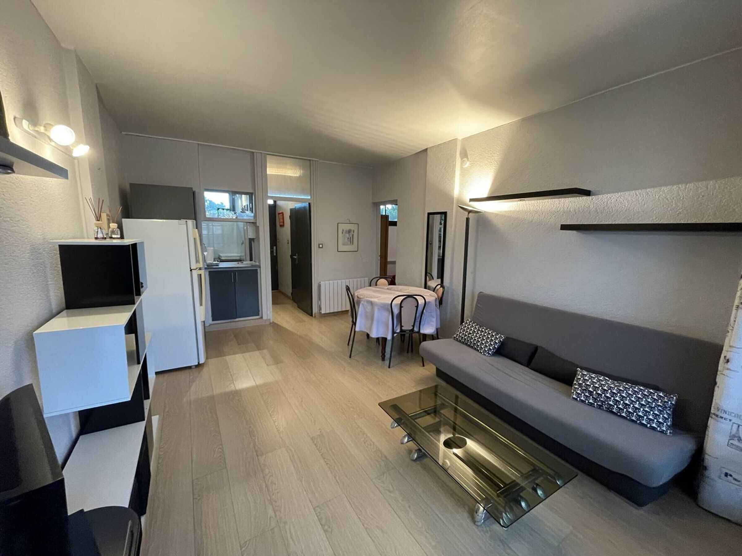 A modern living room with a sofa, a coffee table, and a dining area with a table and chairs.