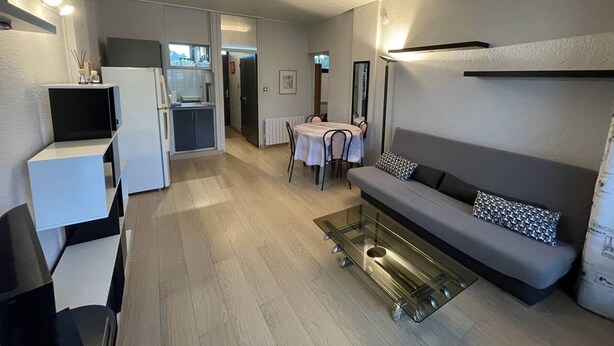 Ett modernt vardagsrum med en soffa, ett soffbord och en matplats med ett bord och stolar.