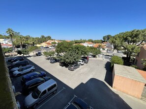 A parking lot with several cars and a large tree in the center. - Apartment, pets welcome, sea view - 4 guests (Saint-Cyprien)