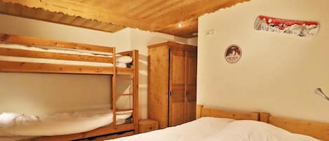Une chambre avec un lit superposé, un plafond en bois, une armoire et un mur orné d’un logo.