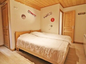 A bedroom with a wooden bed, a wooden wardrobe, and a wooden door. - Apartment with Wi-Fi and parking - 6 guests (Les Gets)