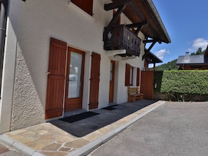 A building with a stone foundation, wooden doors, and a balcony. - Apartment with Wi-Fi and parking - 6 guests (Les Gets)