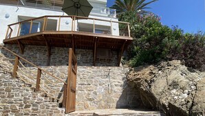 A stone staircase leading to a wooden deck with a glass railing, a sign indicating private property, and a wooden chest on the ground. - Romantic apartment sea view, 2 guests (Le Lavandou)