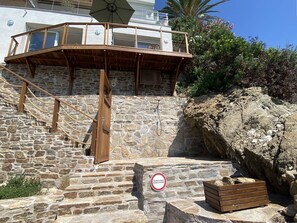 A stone staircase leading to a wooden deck with a glass railing, a sign indicating private property, and a wooden chest on the ground. - Romantic apartment sea view, 2 guests (Le Lavandou)