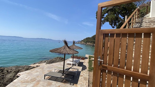 A stone patio with lounge chairs and umbrellas overlooking a body of water. - Romantic apartment sea view, 2 guests (Le Lavandou)