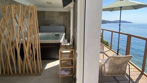 A balcony with a hot tub, a wicker chair, and a view of the sea. - Romantic apartment sea view, 2 guests (Le Lavandou)