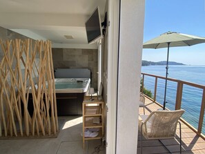 A balcony with a hot tub, a wicker chair, and a view of the sea. - Romantic apartment sea view, 2 guests (Le Lavandou)