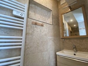 Ein Badezimmer mit einer weißen Badewanne, einem Waschbecken, einem Spiegel und einem Handtuchhalter.