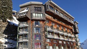 Ein mehrstöckiges Hotel mit Balkonen in einer verschneiten Berglandschaft.