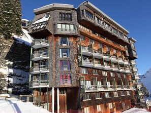 Ein mehrstöckiges Hotel mit Balkonen in einer verschneiten Berglandschaft.
