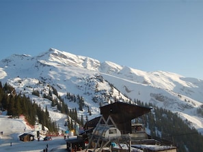 Eine Berglodge mit Seilbahn, schneebedeckten Pisten und blauem Himmel.