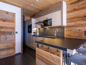 A modern kitchen with wooden accents, stainless steel appliances, and a black countertop. - Stunning 3-Room Apartment in Historic Avoriaz, Ski-in/Ski-out, Free WiFi, Sleeps 6 (Avoriaz)