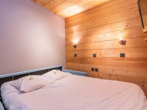 A bedroom with a wooden ceiling, a bed with white bedding, and wall-mounted light fixtures. - Stunning 3-Room Apartment in Historic Avoriaz, Ski-in/Ski-out, Free WiFi, Sleeps 6 (Avoriaz)