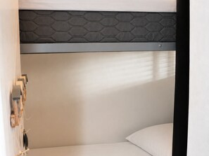 Uma cama beliche com cabeceira de padrão hexagonal e colchão branco.