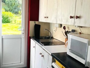 A kitchen with a window, white cabinets, a black countertop, and a microwave. - Comfortable apartment, ski-in access - 4 guests (Les Gets)