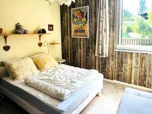 A bedroom with a bed, a poster on the wall, and a window with a view of greenery. - Comfortable apartment, ski-in access - 4 guests (Les Gets)
