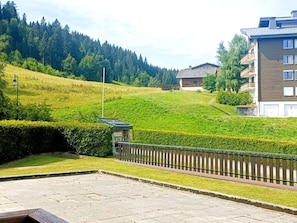 A residential area with a paved patio, a wooden fence, and a building with multiple windows. - Comfortable apartment, ski-in access - 4 guests (Les Gets)
